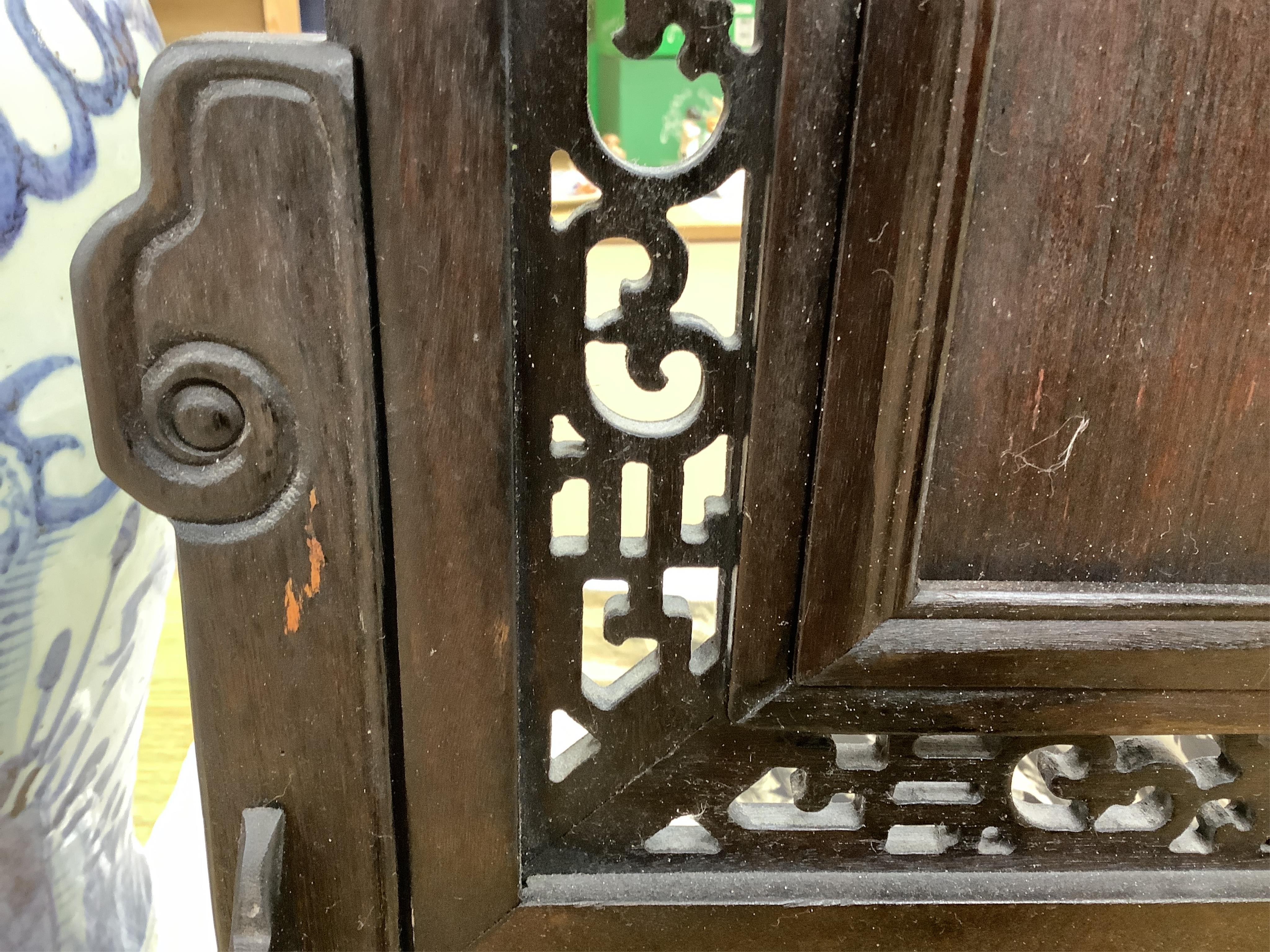 A Chinese carved table screen with a famille rose central plaque, screen 66cm high, plaque 35cm high. Condition - good